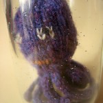 Hand knitted mini octopus sculpture in glass jar