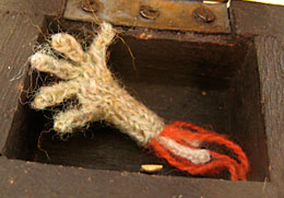 Knitted severed hand in treasure chest with blood.