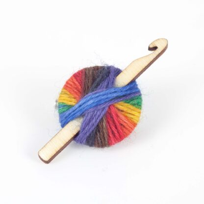 A brooch made with rainbow yarn and a wood crochet hook