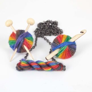 necklace and 2 brooches with pride rainbow yarn